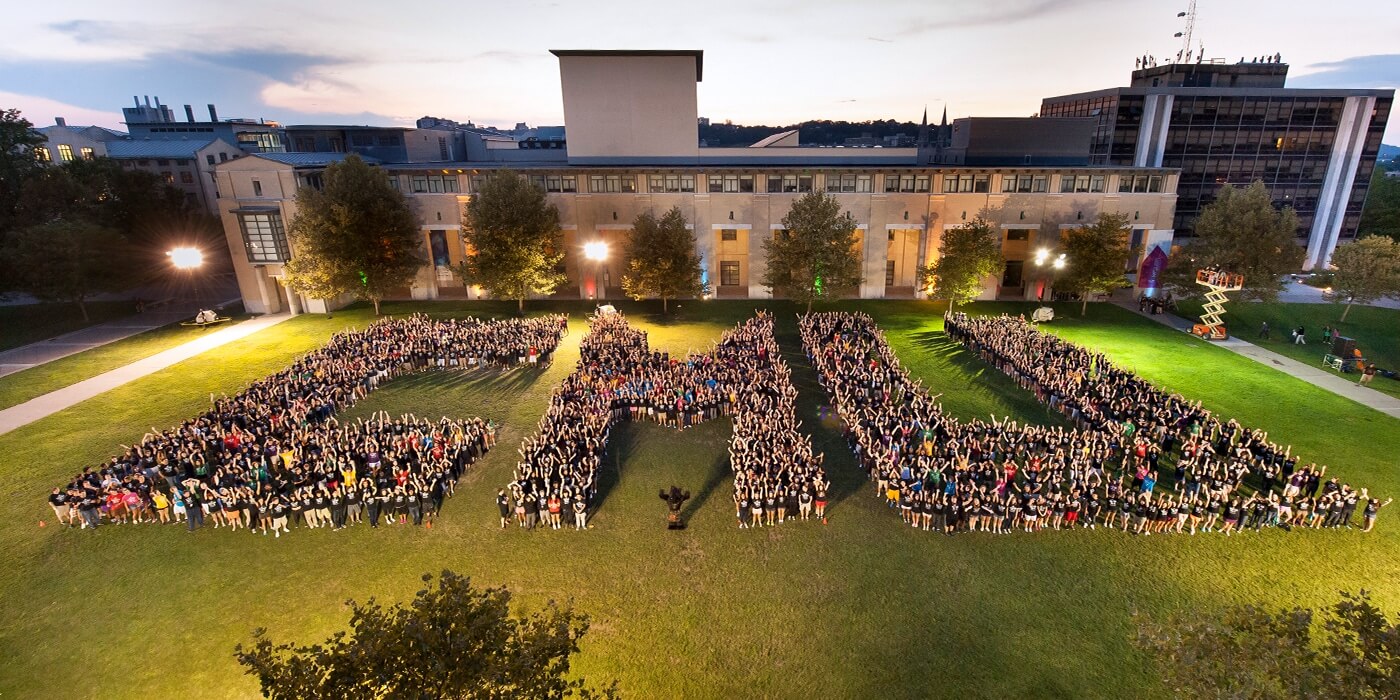 Carnegie Mellon University students gathered on campus at dusk, arranged in the shape of the letters C M U.